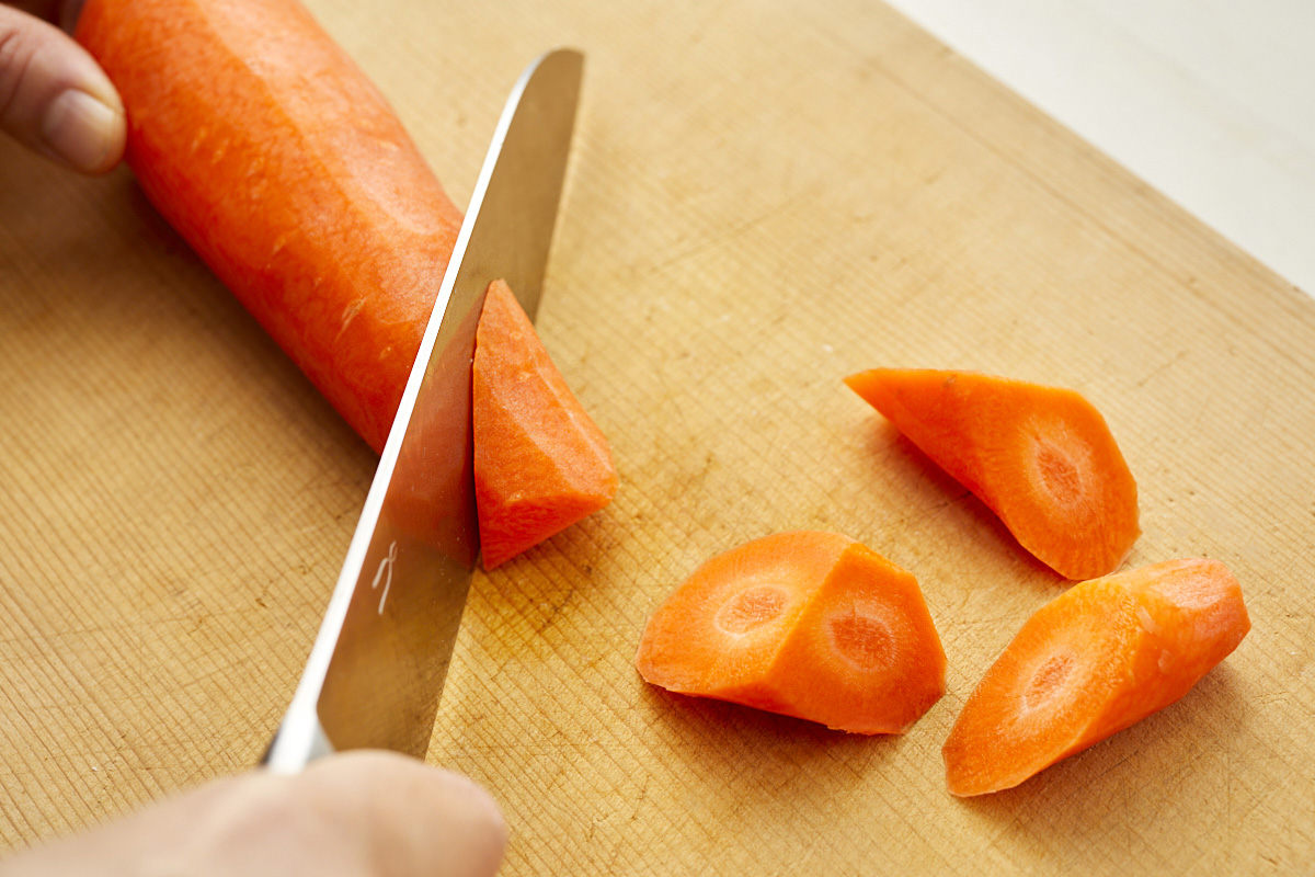 にんじんの先から斜めに包丁を入れて切る様子