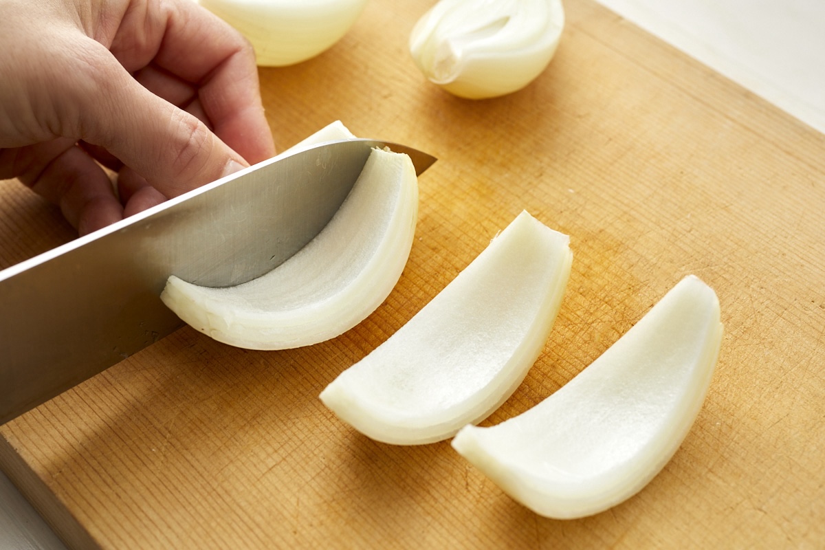 玉ねぎを繊維に沿って縦4等分に切る様子