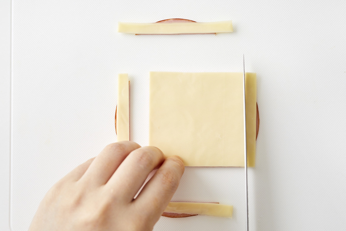 ハムとチーズを重ねて切っている写真