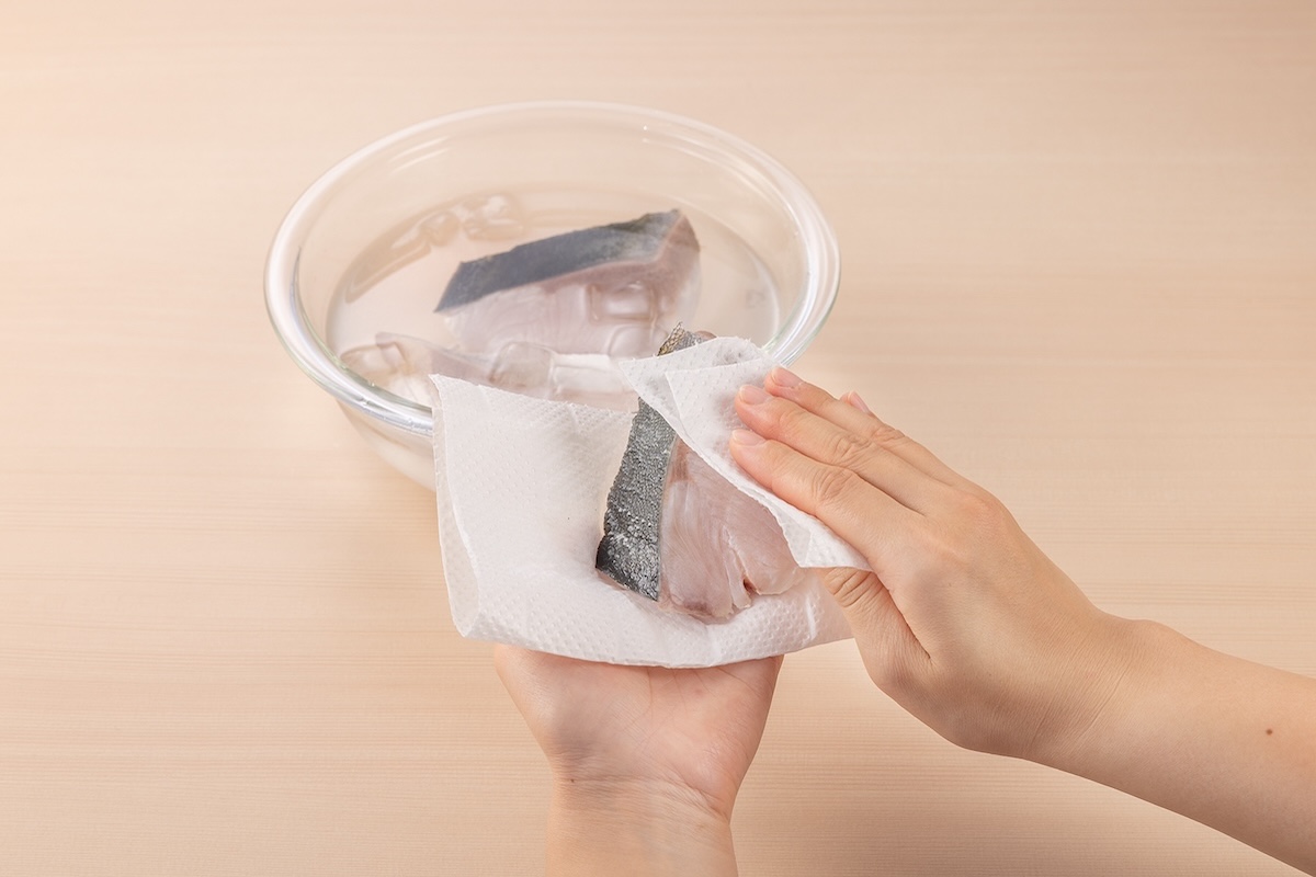 ペーパータオルでぶりの水気を拭き取っている様子