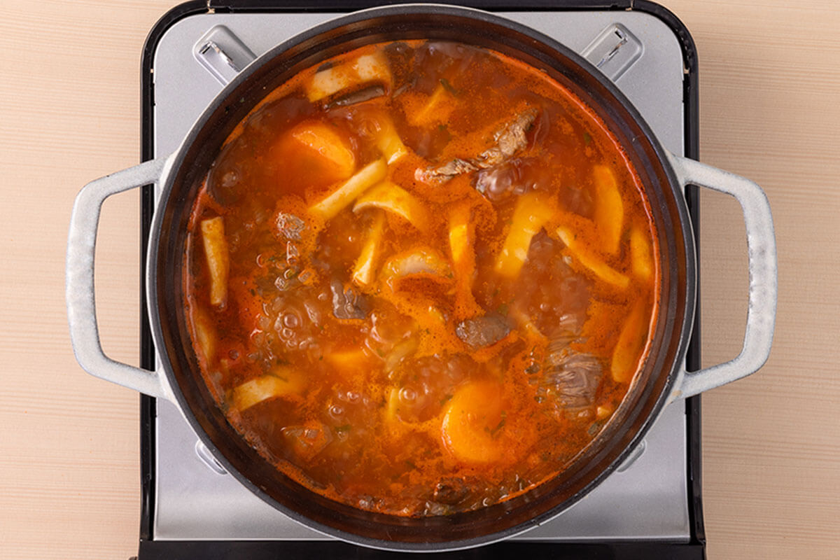 『日本のトマト』とじゃがいもを加えて煮込む様子